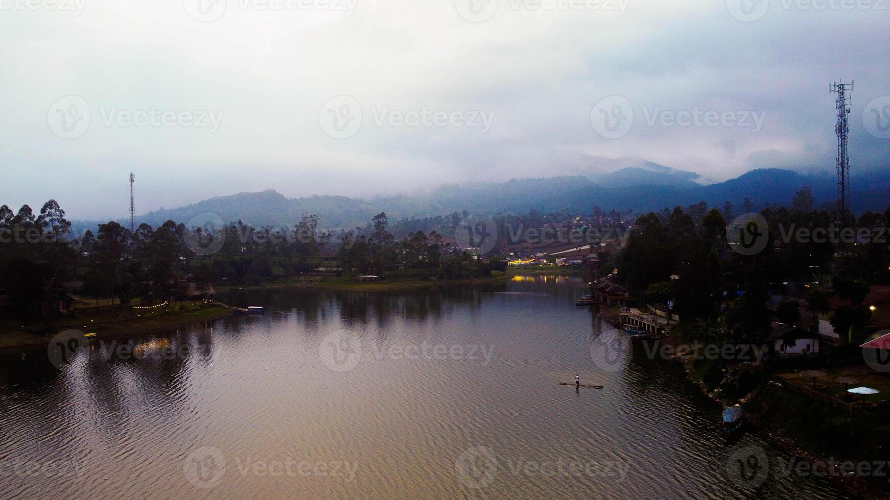 Aerial view of a stunning lake in Bali, a perfect tourist spot where visitors enjoy the serene waters, surrounded by vibrant green nature and tranquil landscapes. photo
