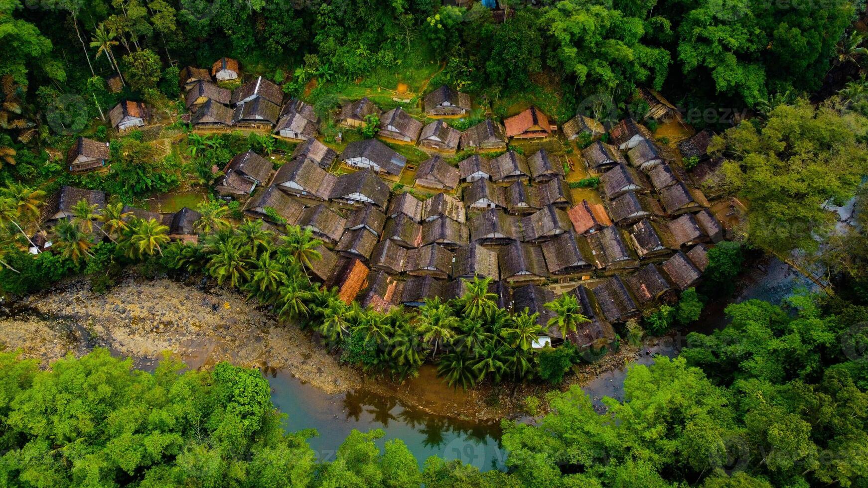 The remote Baduy village is a hidden gem, surrounded by lush greenery and dense trees. This tranquil setting offers a glimpse into a unique culture, photo