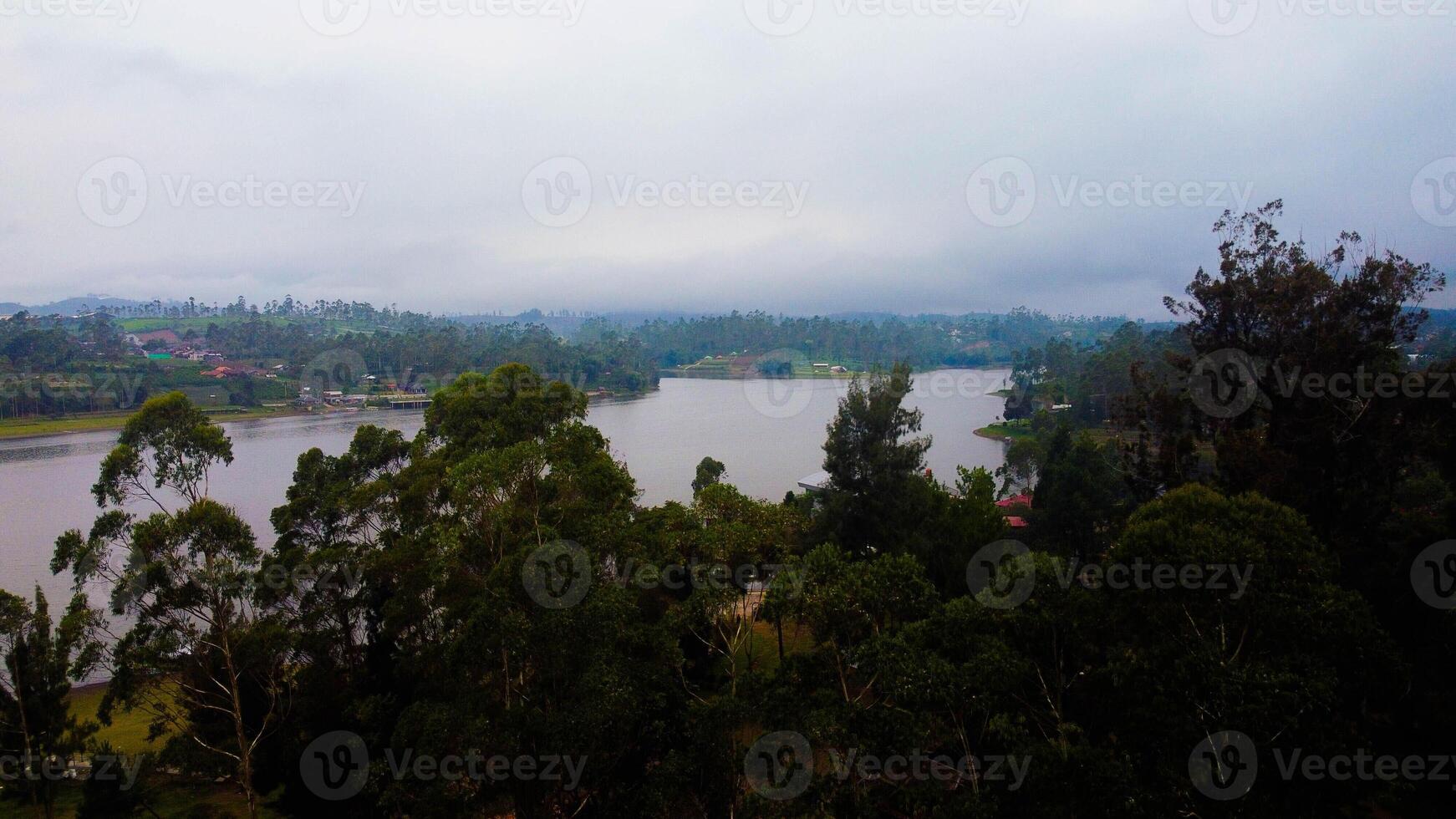 Aerial view of a stunning lake in Bali, a perfect tourist spot where visitors enjoy the serene waters, surrounded by vibrant green nature and tranquil landscapes. photo