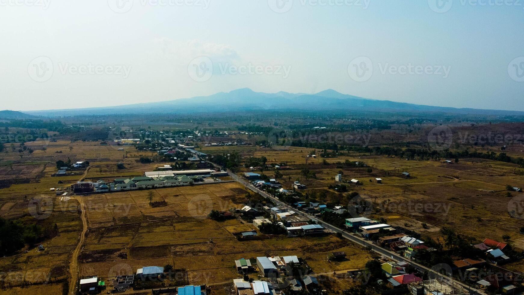 A stunning view of hills in Sumbawa, leading towards Mount Tambora. The vibrant blue sea stretches alongside, creating a breathtaking coastal landscape. photo