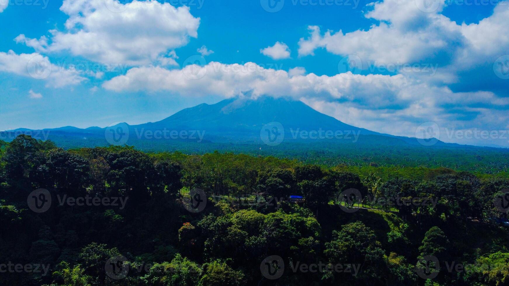 Ranu Bedali Lake in East Java sparkles under a clear blue sky, with Mount Semeru majestically rising in the background. The stunning clouds add to the serene beauty of this breathtaking landscape. photo