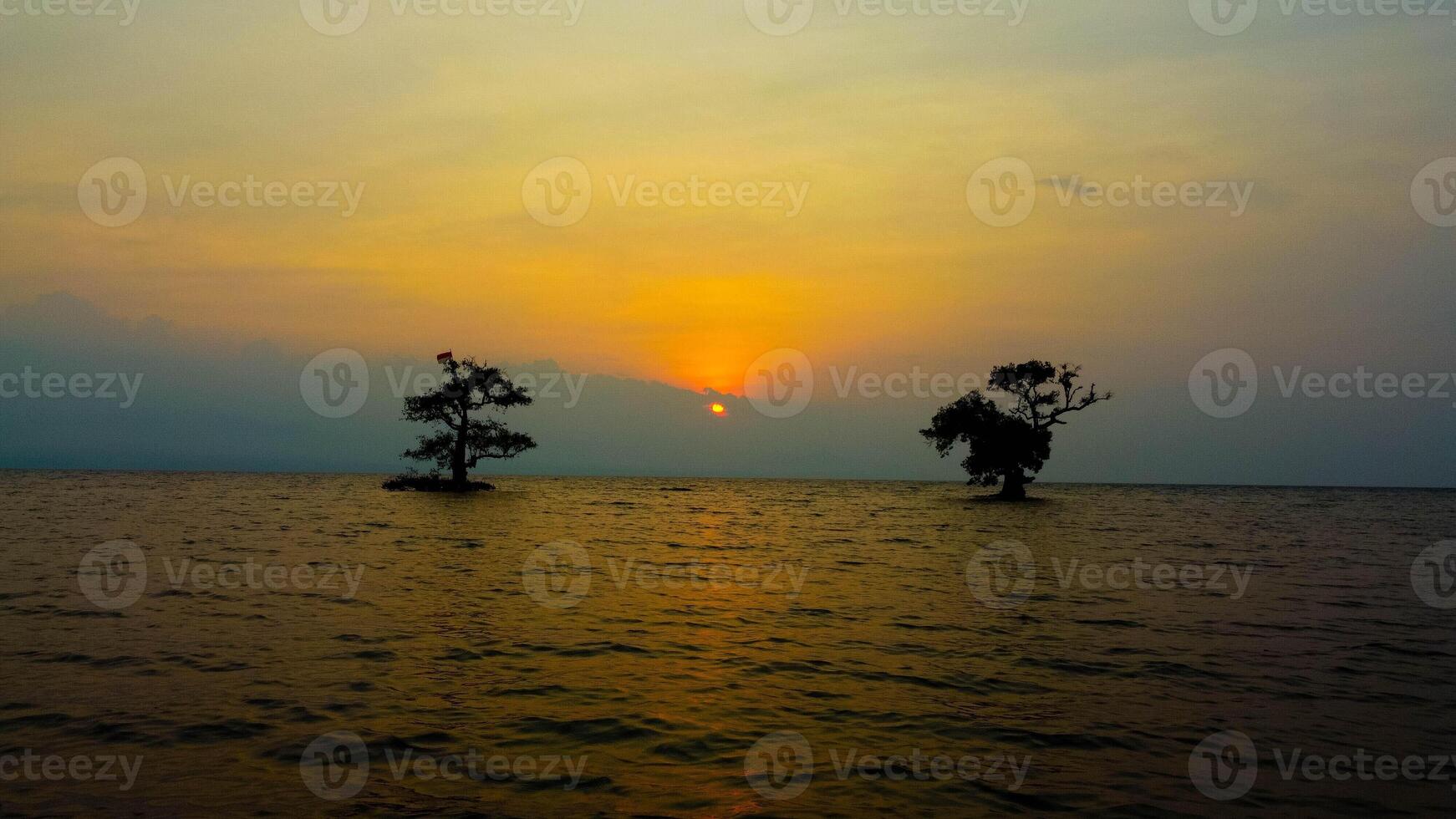 The sunrise casts a golden glow over Gili Trawangan, as the sun rises from the clear blue ocean. The breathtaking beauty creates a perfect tropical morning. photo