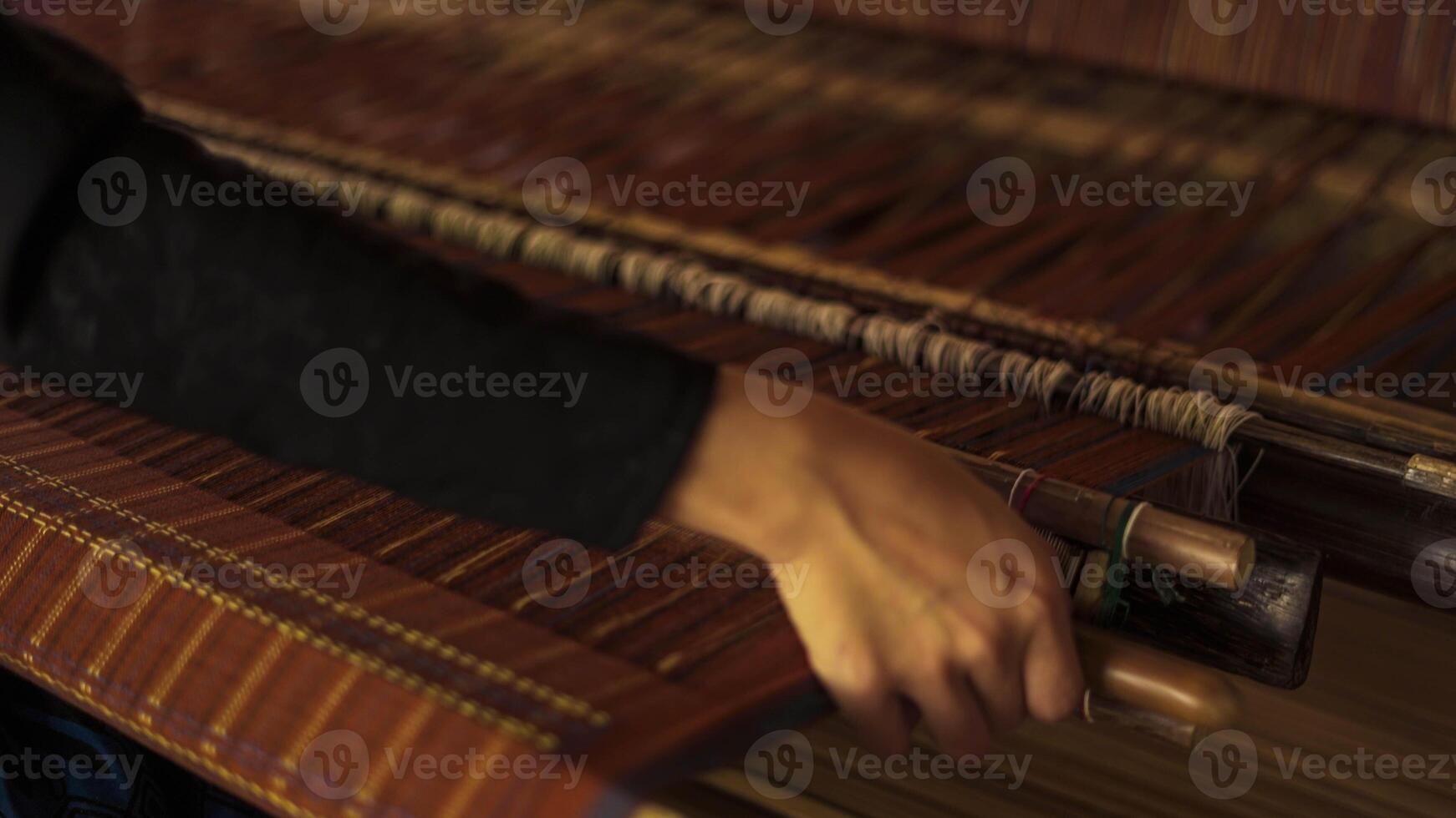 A Baduy woman weaves in front of her home using traditional tools. Her skilled hands create beautiful patterns, preserving cultural heritage and artistry. photo