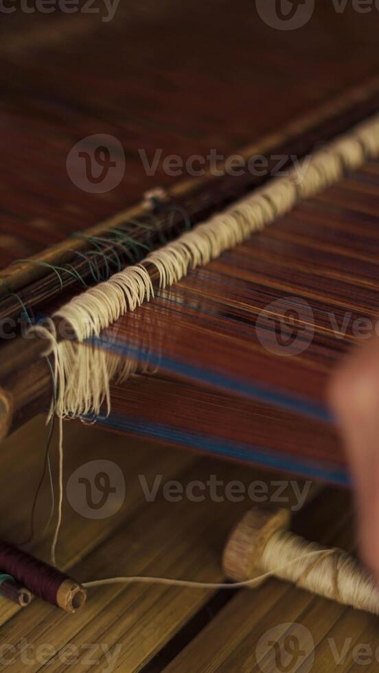 A Baduy woman weaves in front of her home using traditional tools. Her skilled hands create beautiful patterns, preserving cultural heritage and artistry. photo