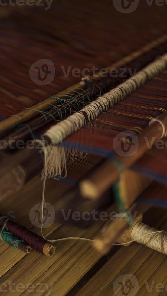 A Baduy woman weaves in front of her home using traditional tools. Her skilled hands create beautiful patterns, preserving cultural heritage and artistry. photo