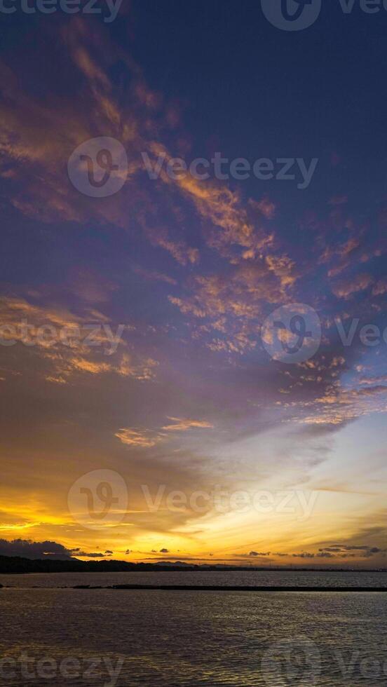 A stunning sunset in Indonesia paints the sky in vibrant oranges and reds. People gather, savoring the breathtaking view and the tranquility it brings. photo