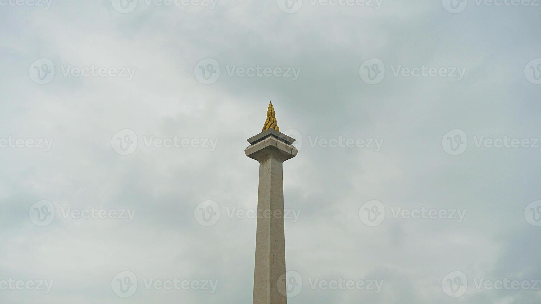 The iconic Monas in Jakarta stands tall against a backdrop of beautiful clouds and lush green grass photo