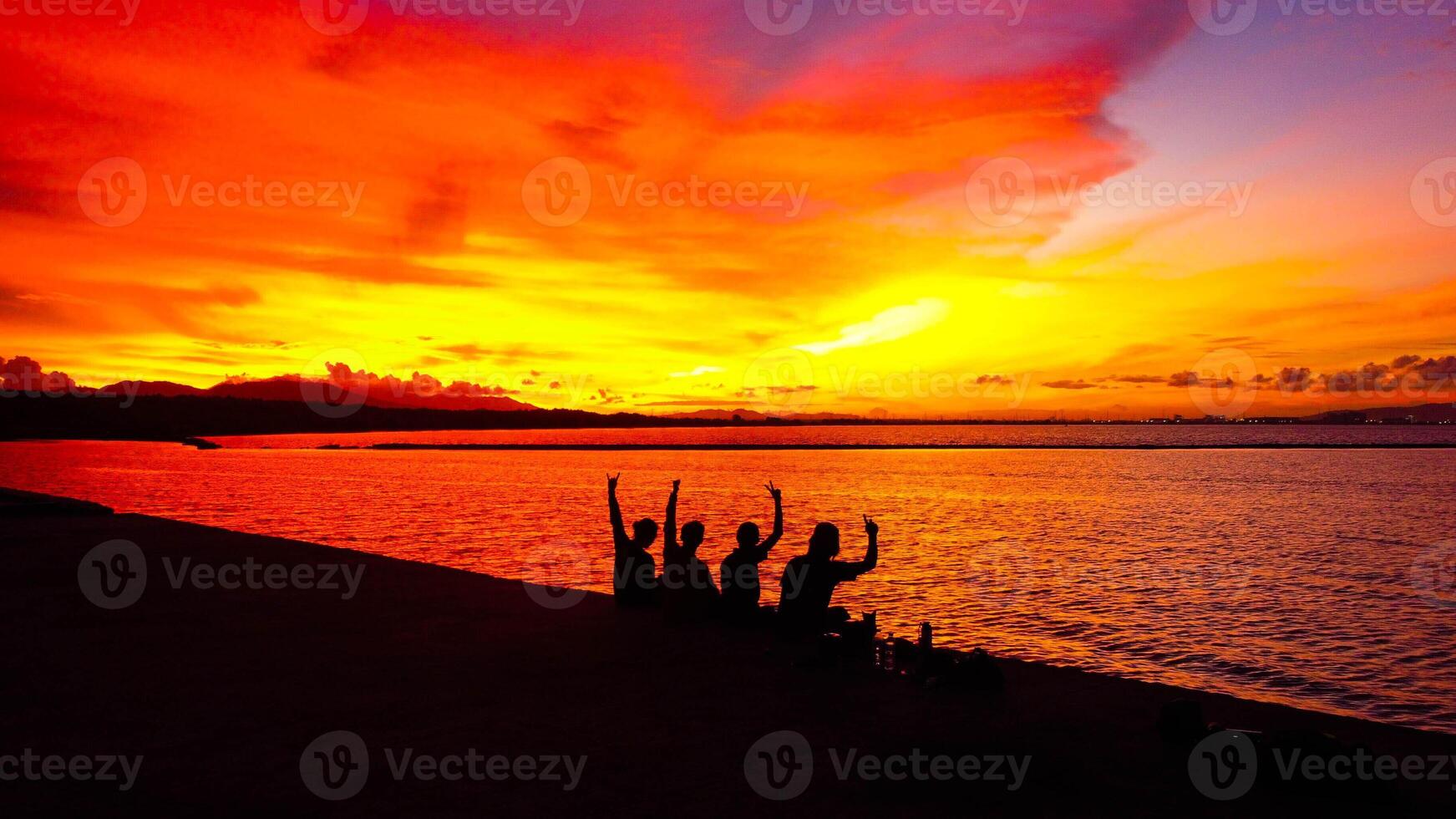 A stunning sunset in Indonesia paints the sky in vibrant oranges and reds. People gather, savoring the breathtaking view and the tranquility it brings. photo