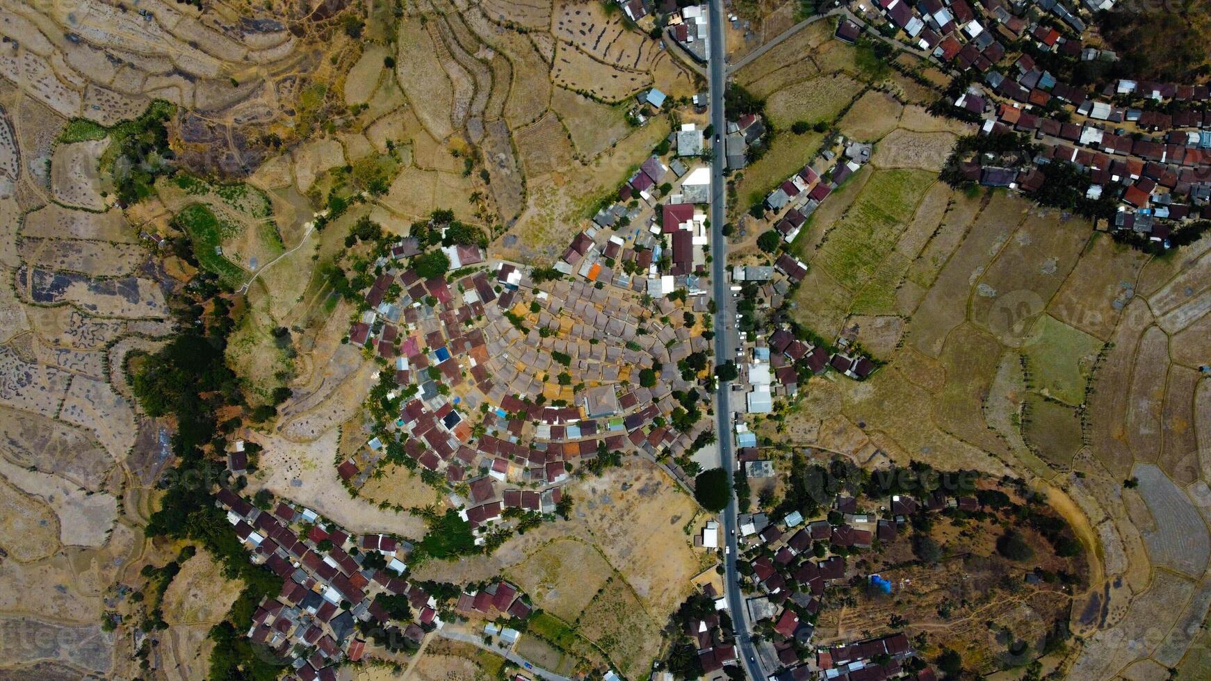 An aerial view of Sade Village in Lombok reveals lush farmland and densely populated homes under the bright midday sun, showcasing vibrant community life. photo