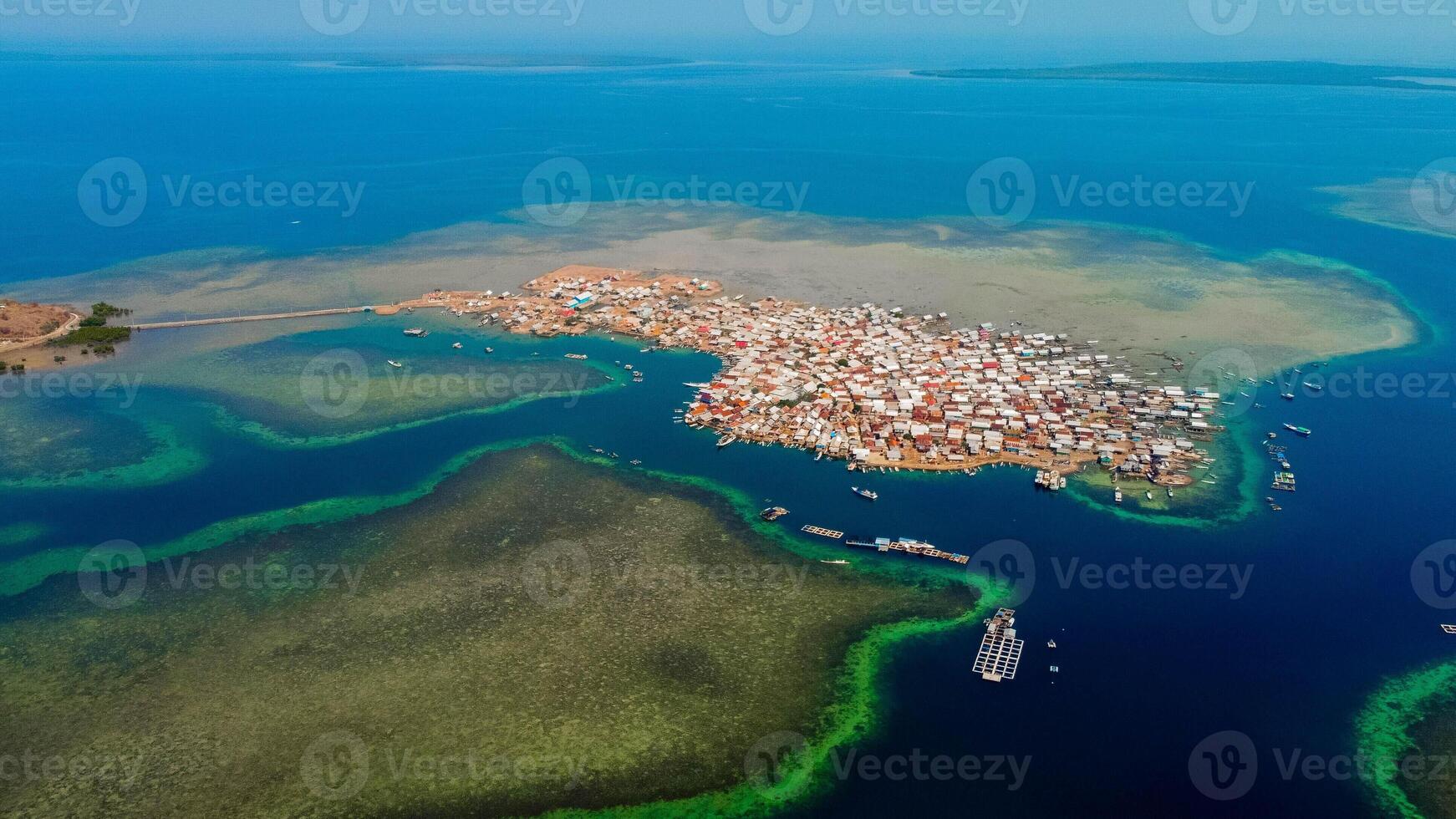 Explore stunning aerial footage of the world's most unique at Bungin Island, densely populated island, nestled in vibrant blue waters with 3,000 residents in Nusa Tenggara Barat, Indonesia photo