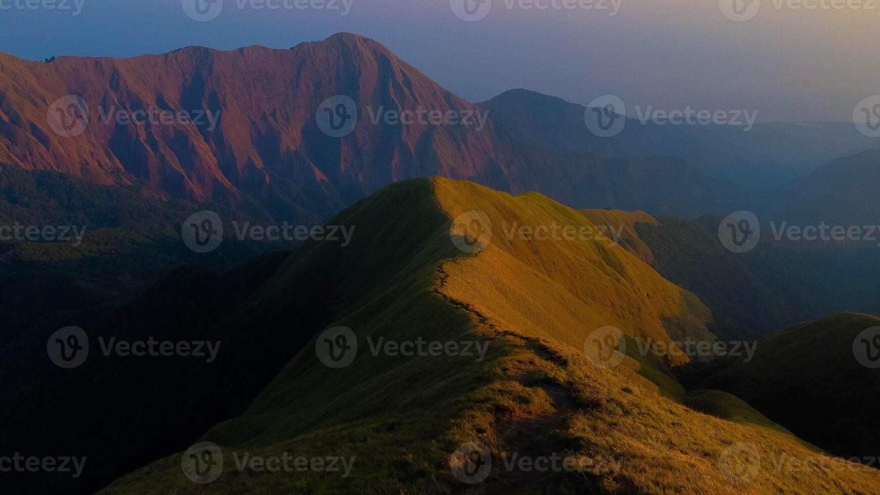 Experience breathtaking aerial views of the rolling hills in Sembalun, at the foot of Mount Rinjani, with expansive savanna turning golden at sunrise. photo