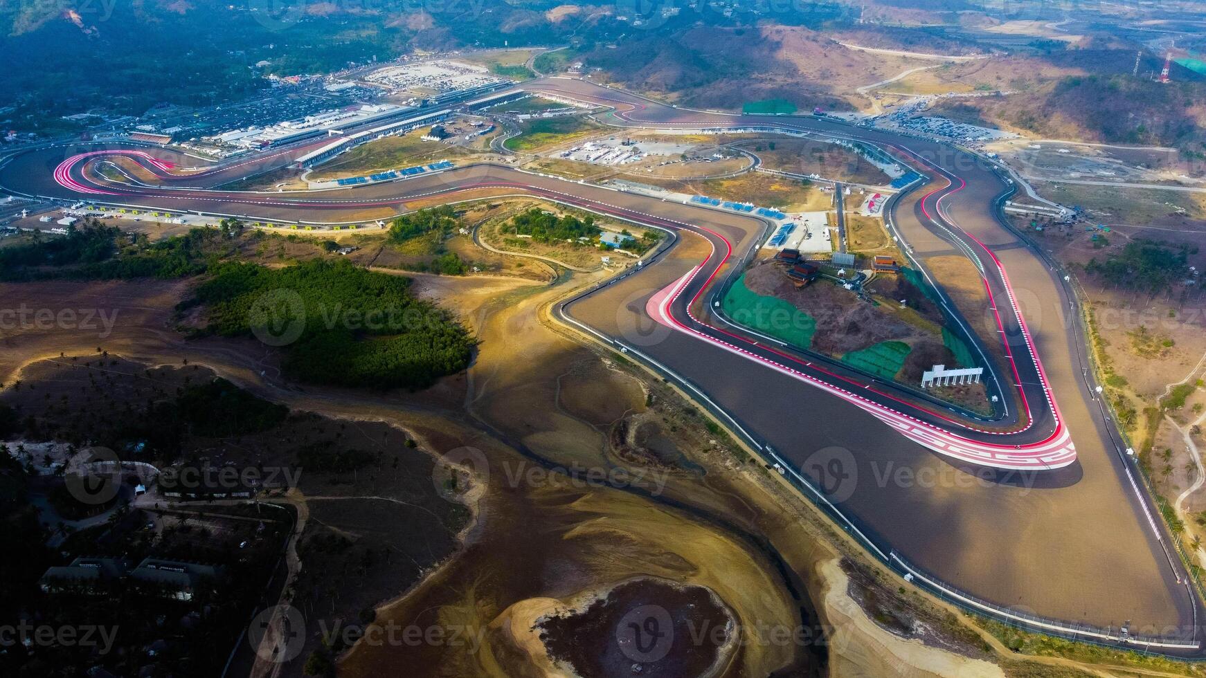 Experience stunning aerial views of hills behind the Mandalika circuit in Lombok, with a breathtaking sunset atmosphere as the camera glides through the clouds. photo