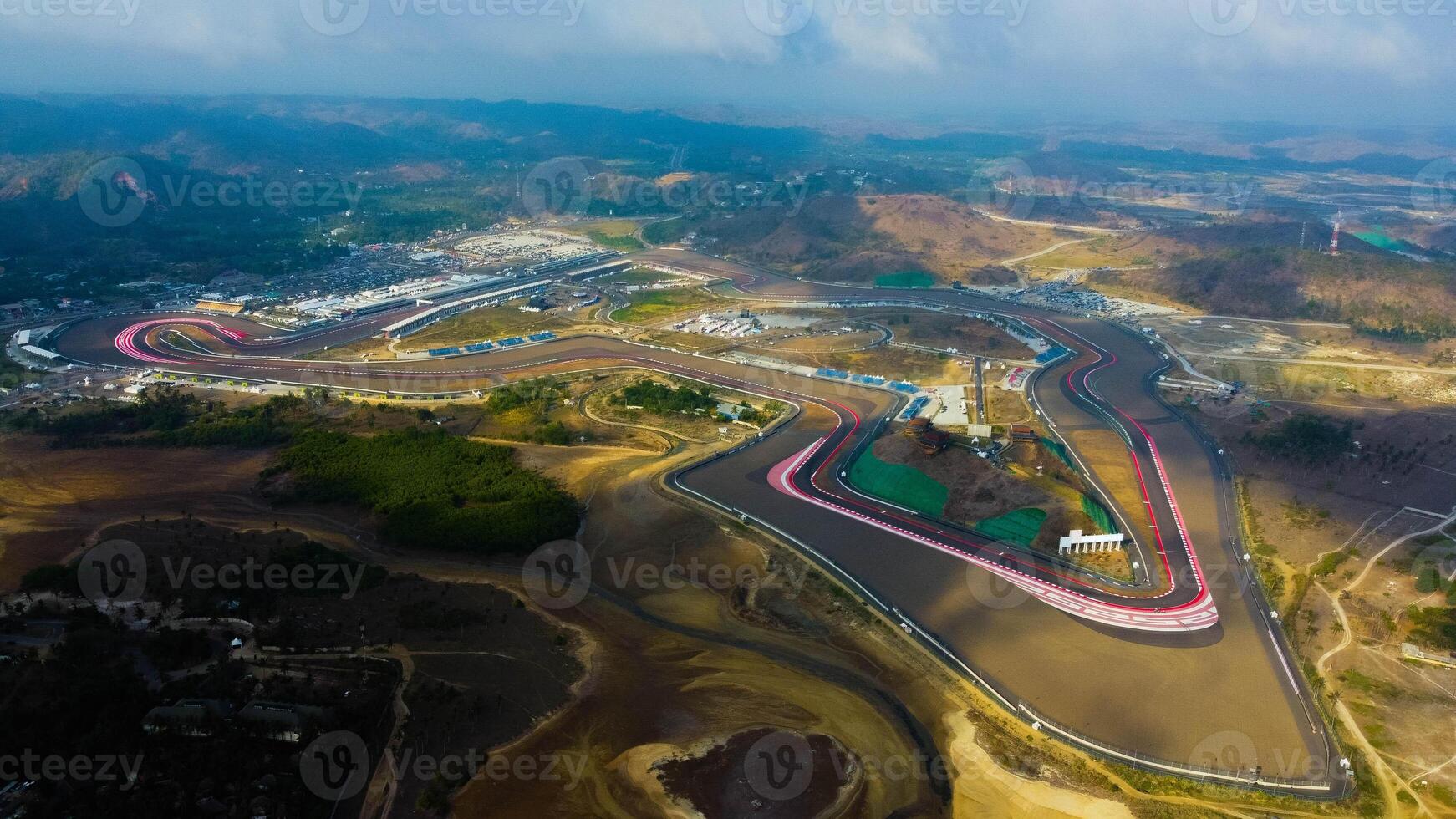 Experience stunning aerial views of hills behind the Mandalika circuit in Lombok, with a breathtaking sunset atmosphere as the camera glides through the clouds. photo