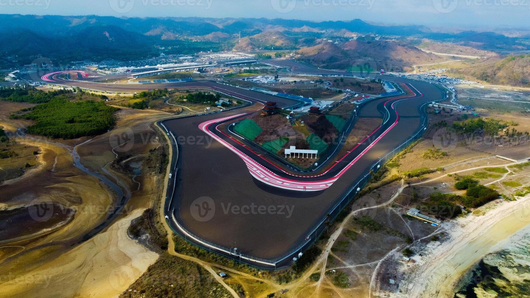 Experience stunning aerial views of hills behind the Mandalika circuit in Lombok, with a breathtaking sunset atmosphere as the camera glides through the clouds. photo