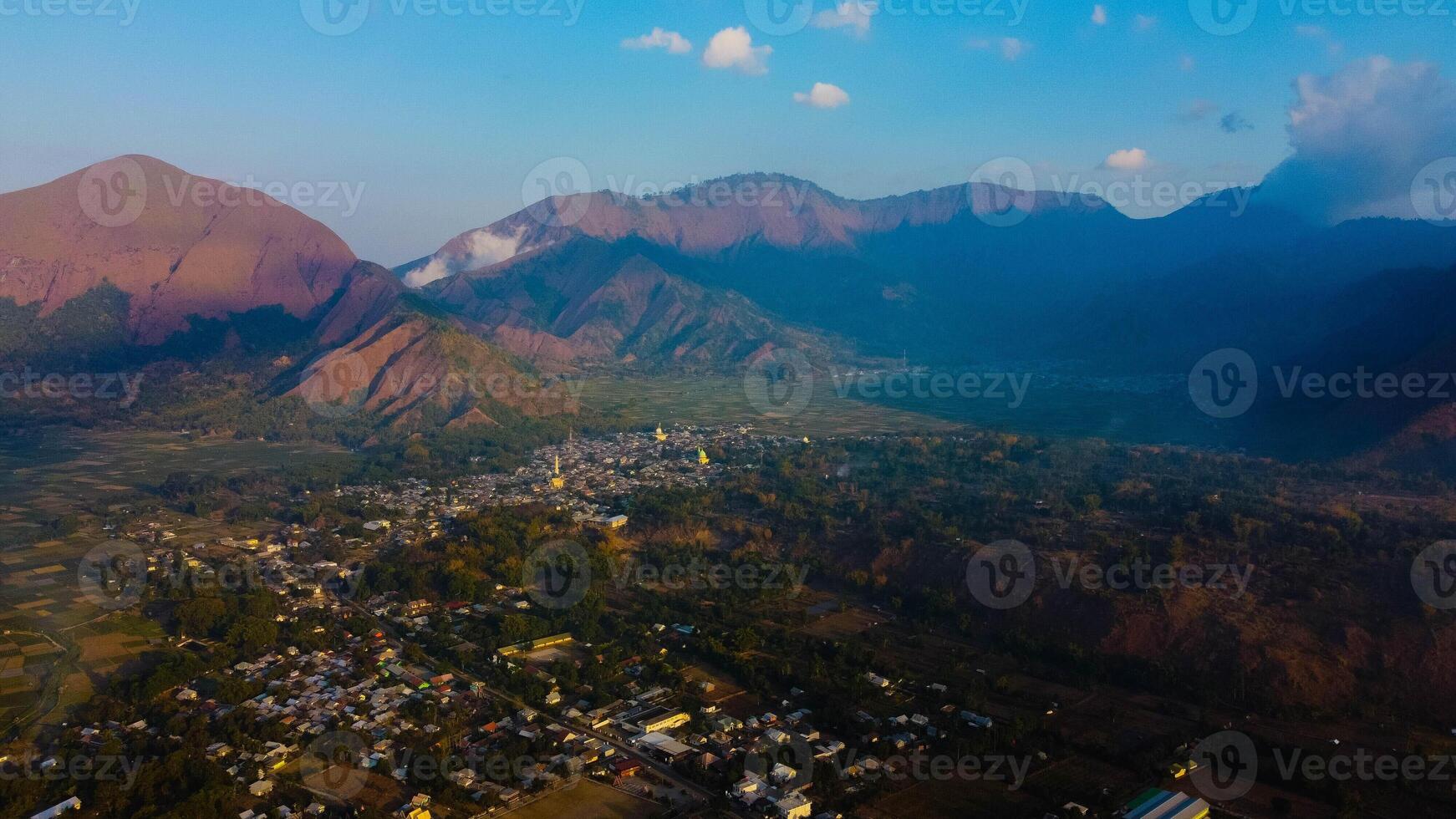 Experience breathtaking aerial views of the rolling hills in Sembalun, at the foot of Mount Rinjani, with expansive savanna turning golden at sunrise. photo