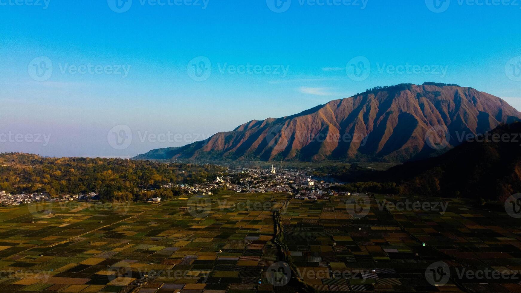 Experience breathtaking aerial views of the rolling hills in Sembalun, at the foot of Mount Rinjani, with expansive savanna turning golden at sunrise. photo