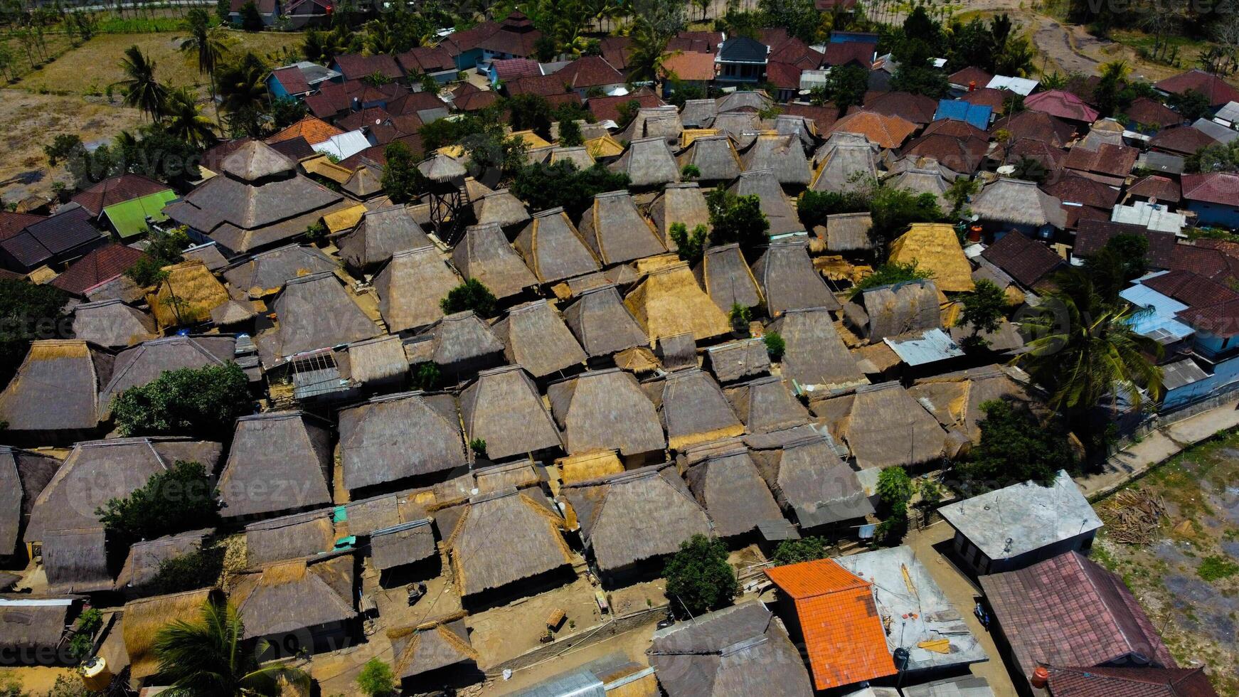 An aerial view of Sade Village in Lombok reveals lush farmland and densely populated homes under the bright midday sun, showcasing vibrant community life. photo