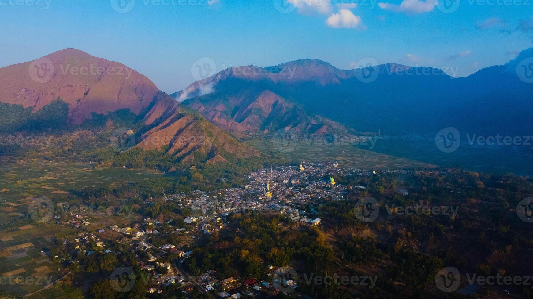 Experience breathtaking aerial views of the rolling hills in Sembalun, at the foot of Mount Rinjani, with expansive savanna turning golden at sunrise. photo