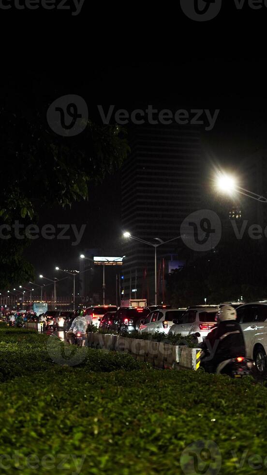 A busy city street with many people and vehicle. Concept of hustle and bustle, with people walking and cars driving in a busy urban environmen photo