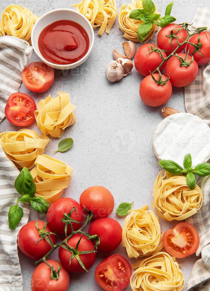Italian food background featuring tomatoes, pasta, garlic, cheese, basil and tomato sauce creating a frame photo