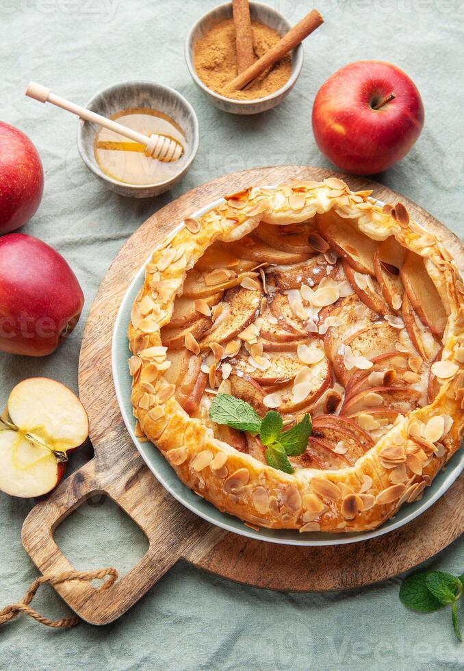 Delicious homemade apple tart displayed on a wooden board surrounded by fresh apples and honey photo