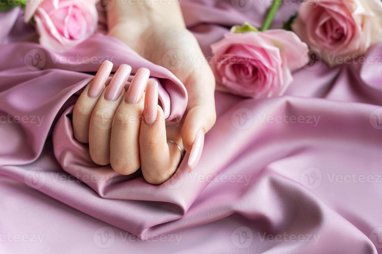 Woman showing pink manicure holding pink rose on pink silk background photo