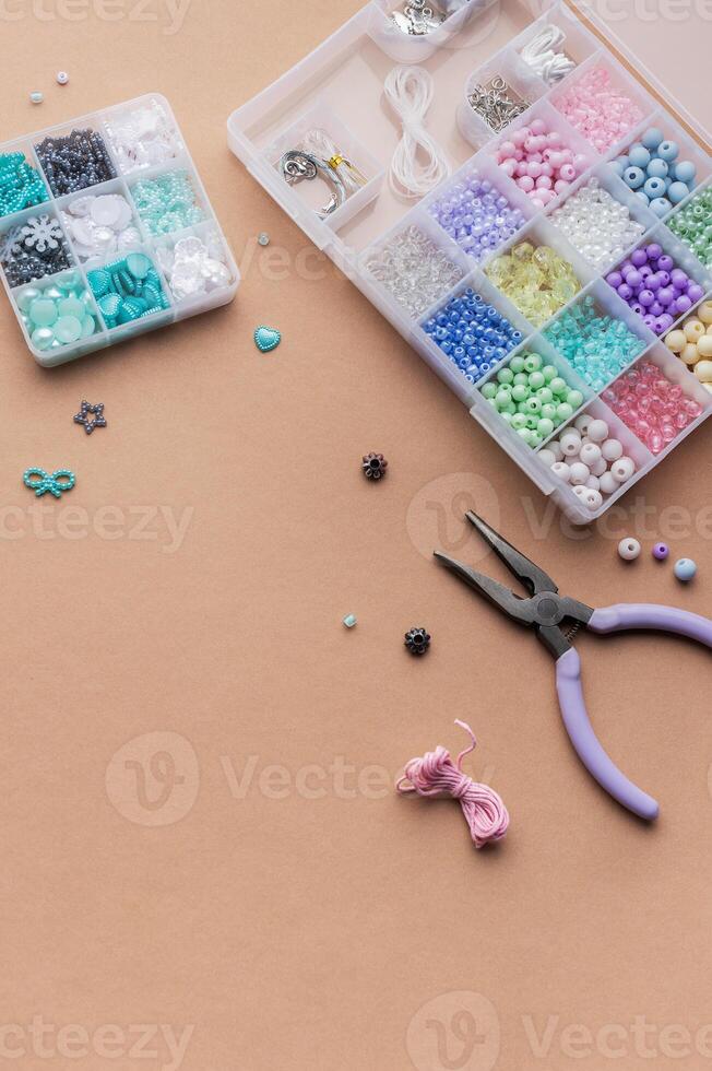 Crafting with colorful beads on a flat workspace with tools and containers in bright daylight photo