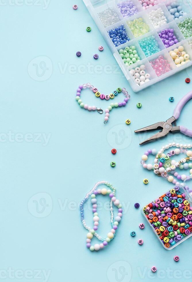 Colorful beads and pliers creating friendship bracelets on blue background photo