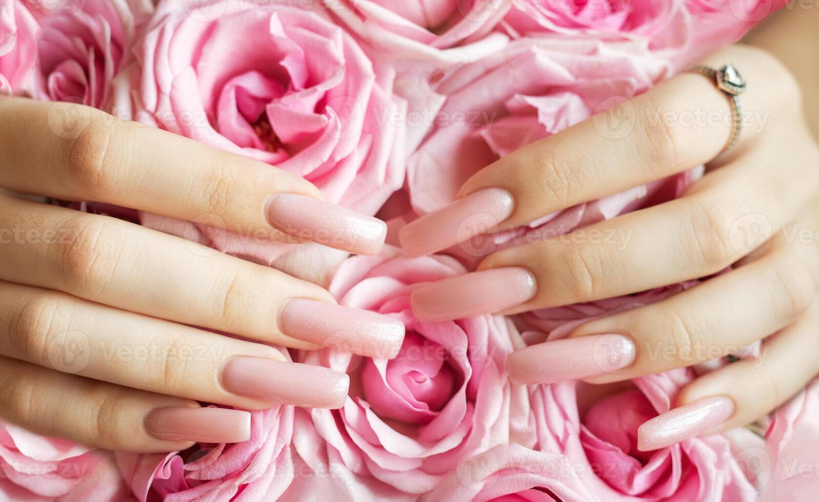 Woman showing pink manicure and ring on bouquet of roses photo