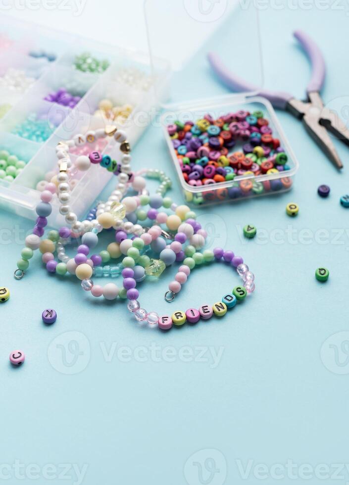 Colorful beads and pliers creating friendship bracelets on blue background photo
