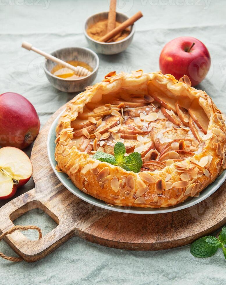 Delicious homemade apple tart displayed on a wooden board surrounded by fresh apples and honey photo