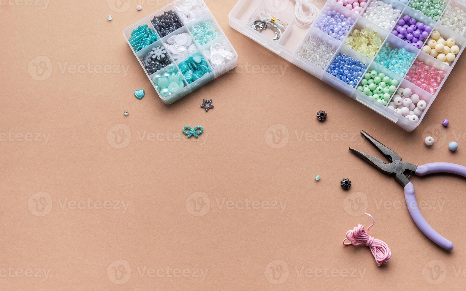 Crafting with colorful beads on a flat workspace with tools and containers in bright daylight photo