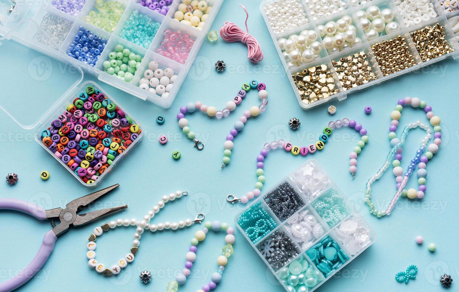 Colorful assortment of beads and jewelry-making tools on a blue surface with completed bracelets photo