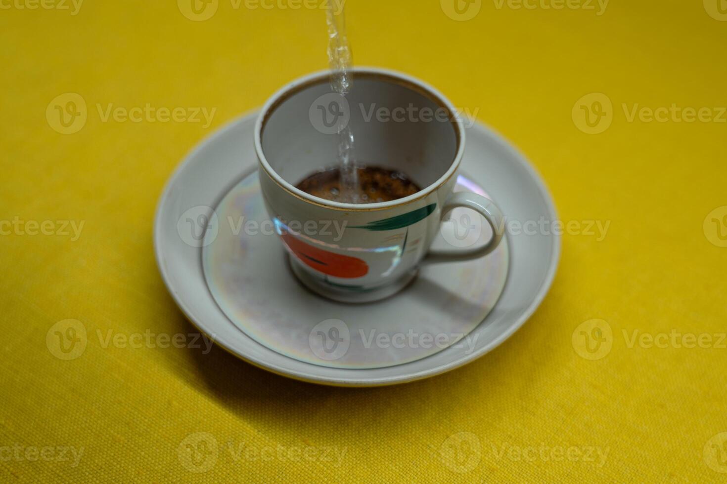 I pour boiling water into a mug with instant coffee. A mug in a saucer photo