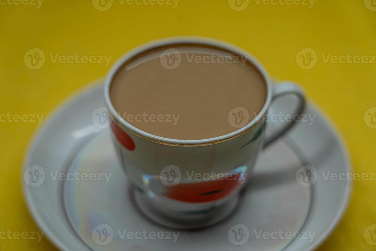 A mug of coffee with milk. Mug in a saucer on a yellow background. Top-down view photo