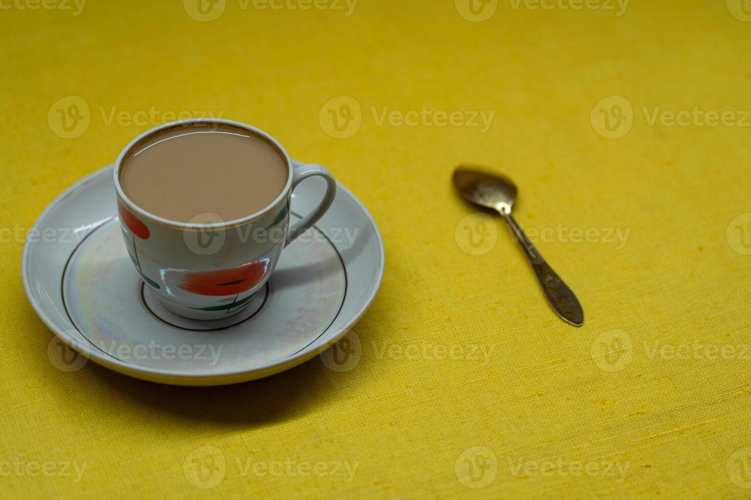 A golden spoon with coffee. Mug in a saucer on a yellow background. Coffee time photo