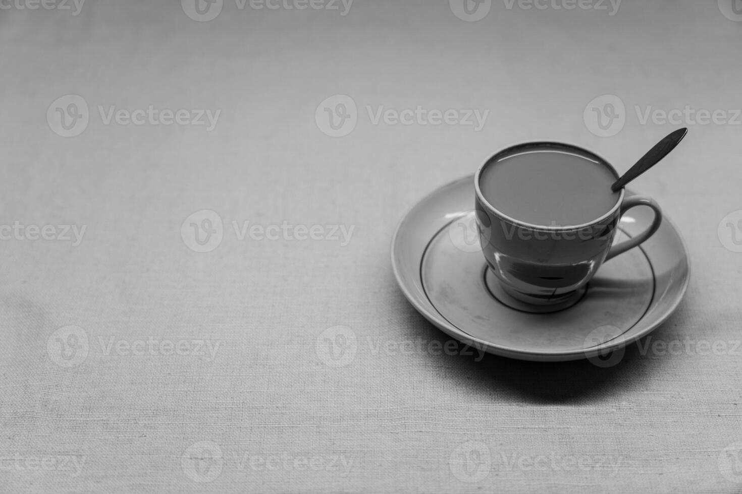 A golden spoon with coffee. A mug in a saucer on a yellow background photo