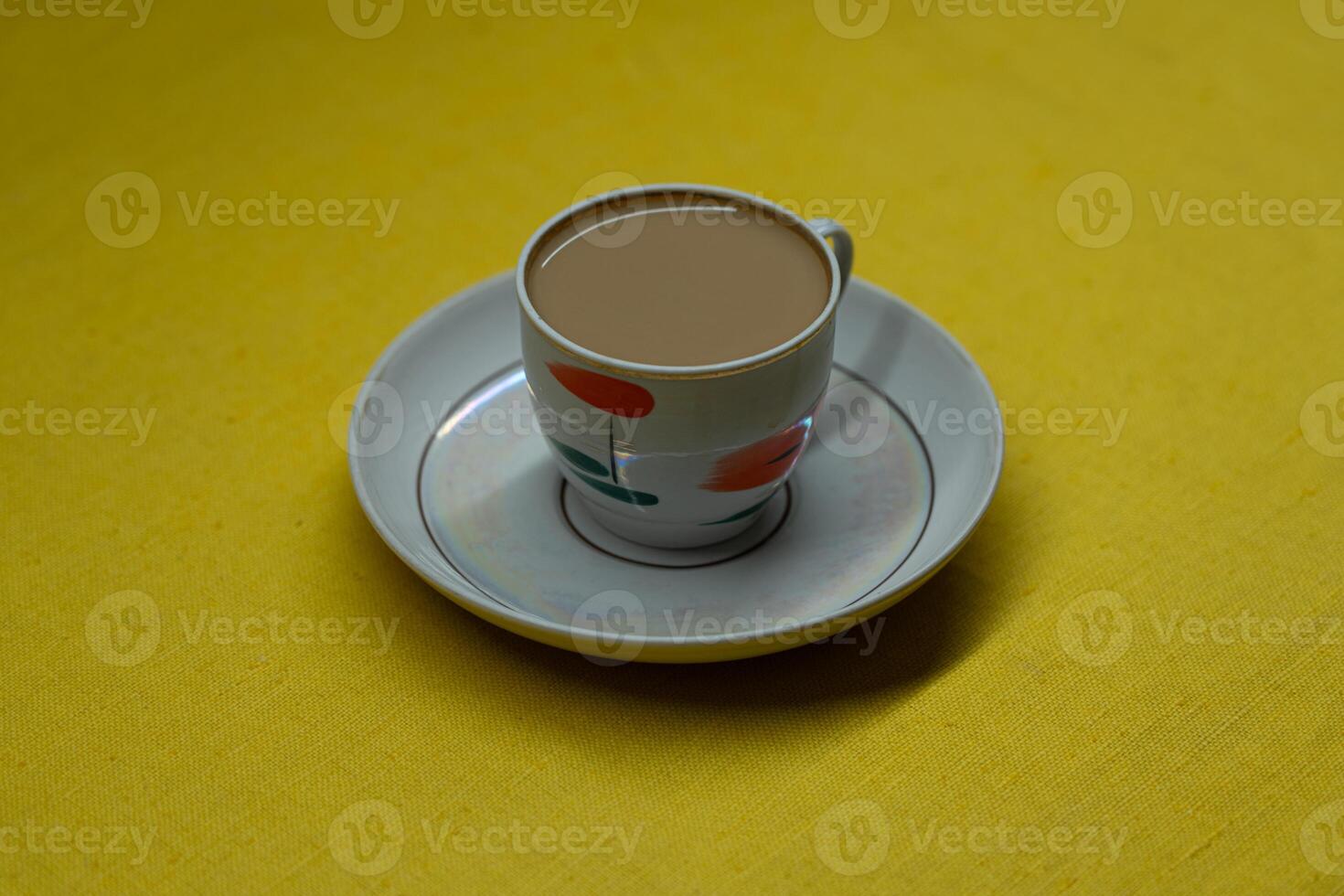 A mug of coffee with milk. Mug in a saucer on a yellow background. Top-down view photo