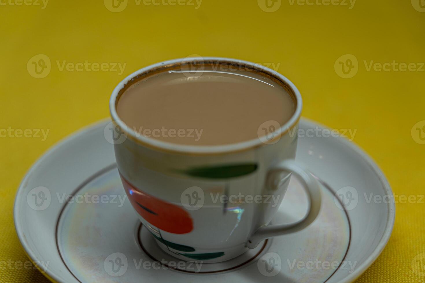A mug of coffee with milk. Mug in a saucer on a yellow background. Top-down view photo