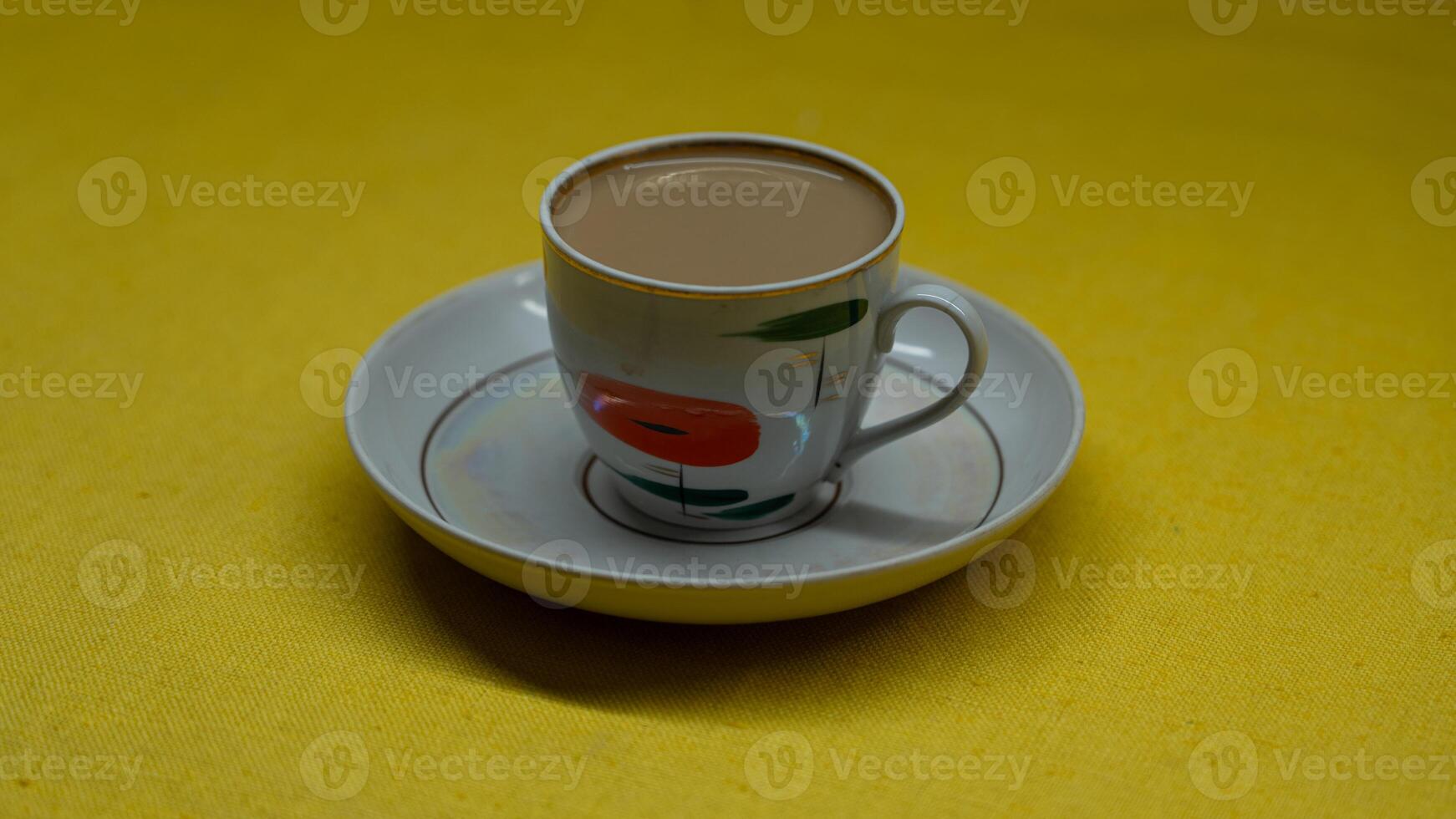 A mug of coffee with milk. Mug in a saucer on a yellow background. Top-down view photo