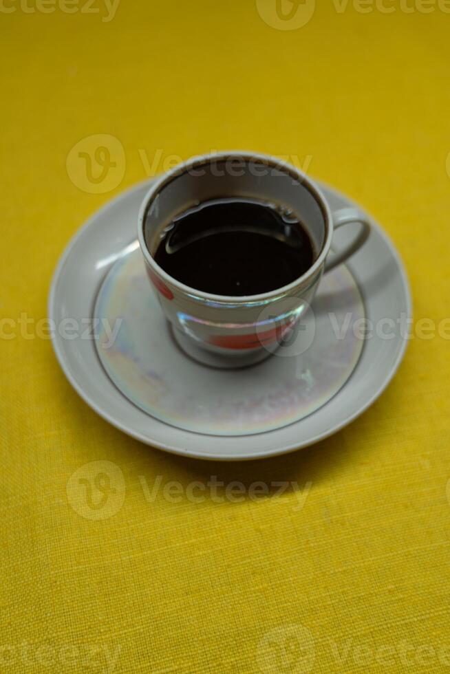 Instant coffee in a mug. A mug in a saucer on a yellow background. Top-down view photo