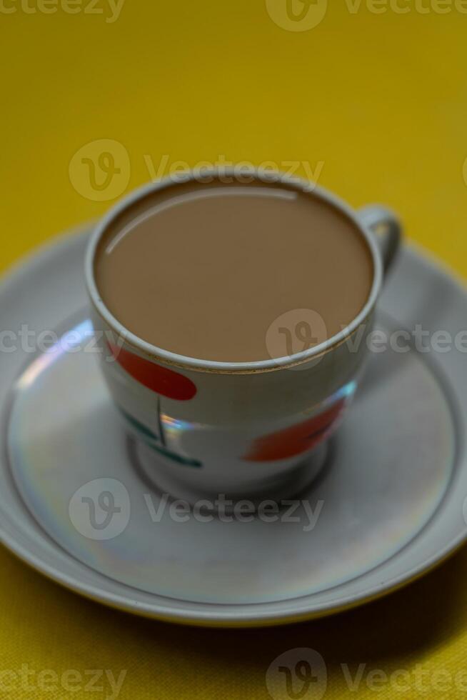 A mug of coffee with milk. Mug in a saucer on a yellow background. Top-down view photo