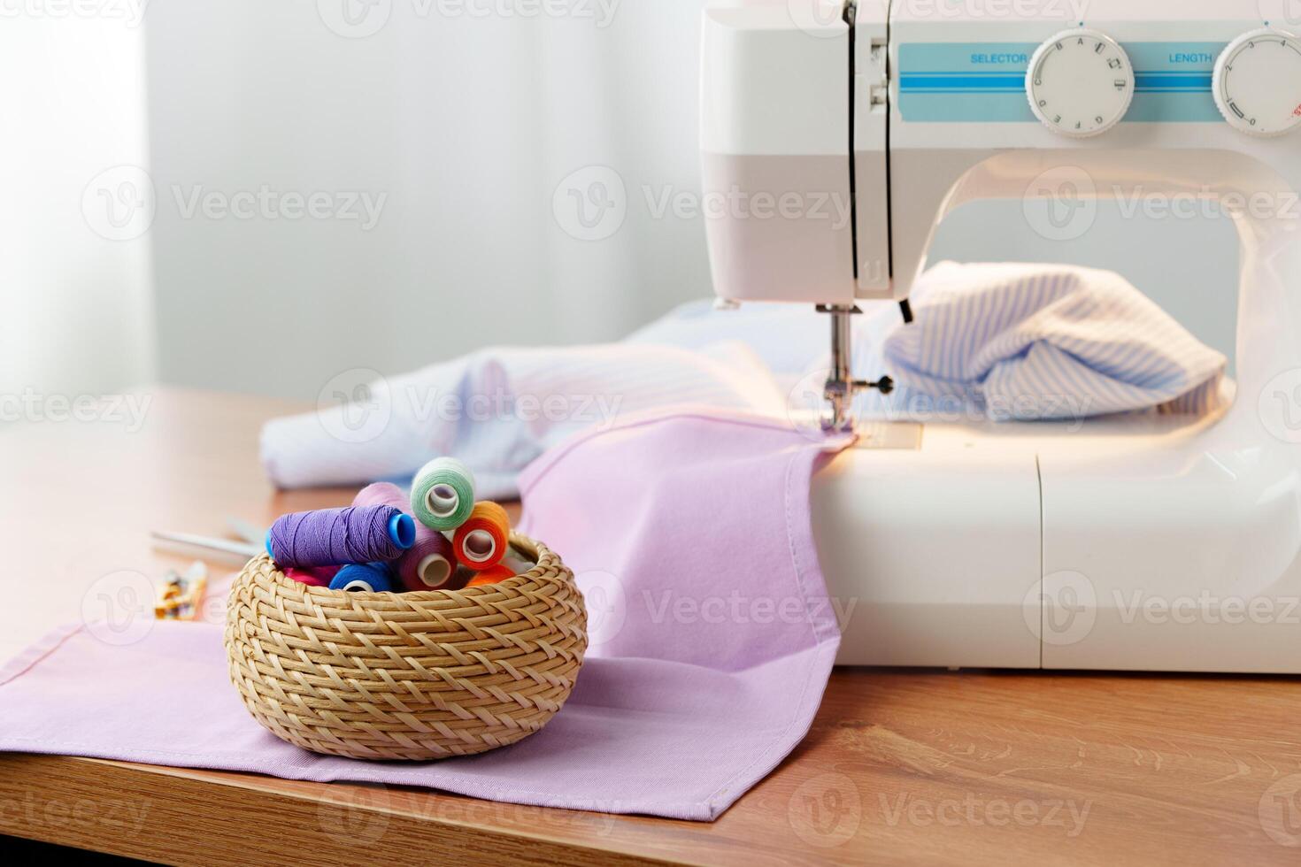 Sewing machine in use on a wooden table, stitching a light fabric in a well-lit indoor workspace photo