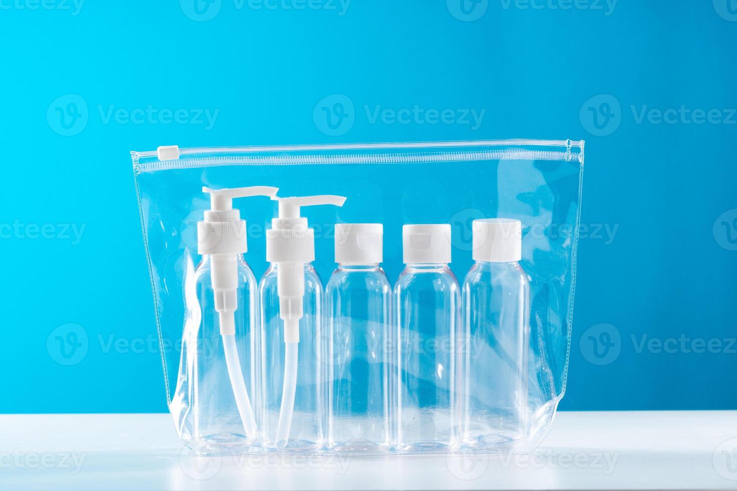 Transparent toiletry bag containing various travel-sized containers on a bright blue background photo