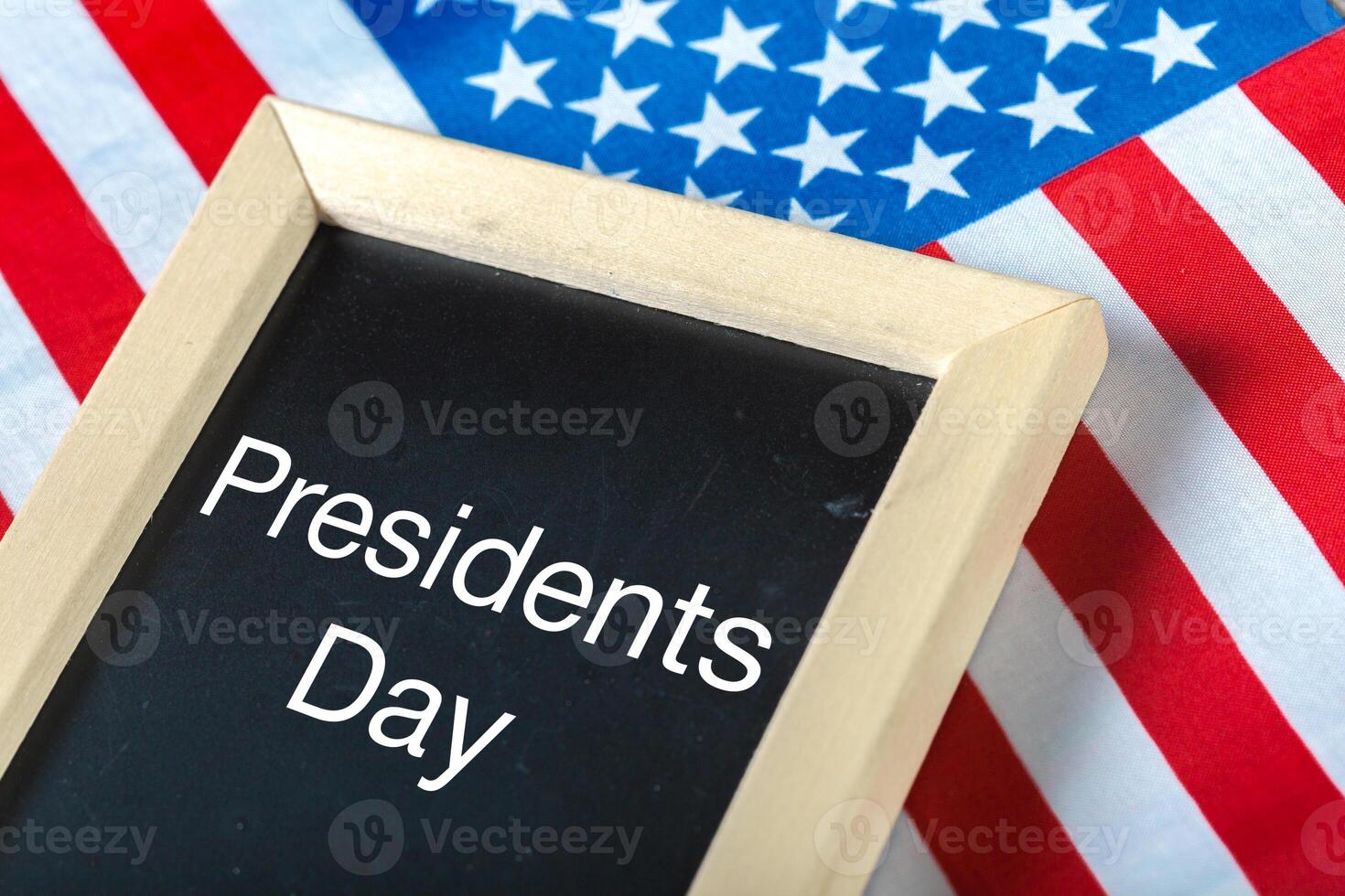 the text happy presidents day written in a chalkboard and a flag of the United States photo