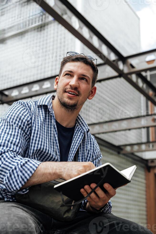 A person writes in a notebook while sitting on a park bench photo