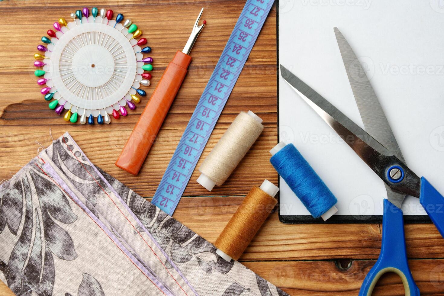 Colorful sewing supplies arranged around a blank clipboard on a wooden table photo