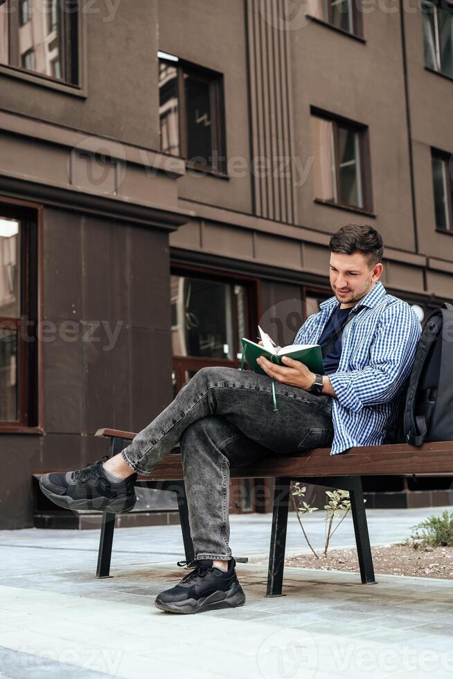 A person writes in a notebook while sitting on a park bench photo