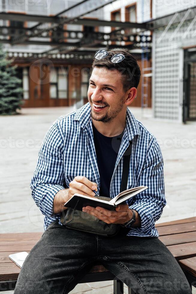 A person writes in a notebook while sitting on a park bench photo