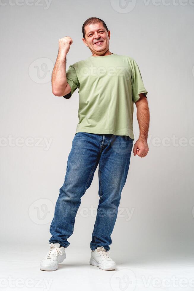 Happy elderly man celebrating a victory with joyful gestures in a light-colored setting photo